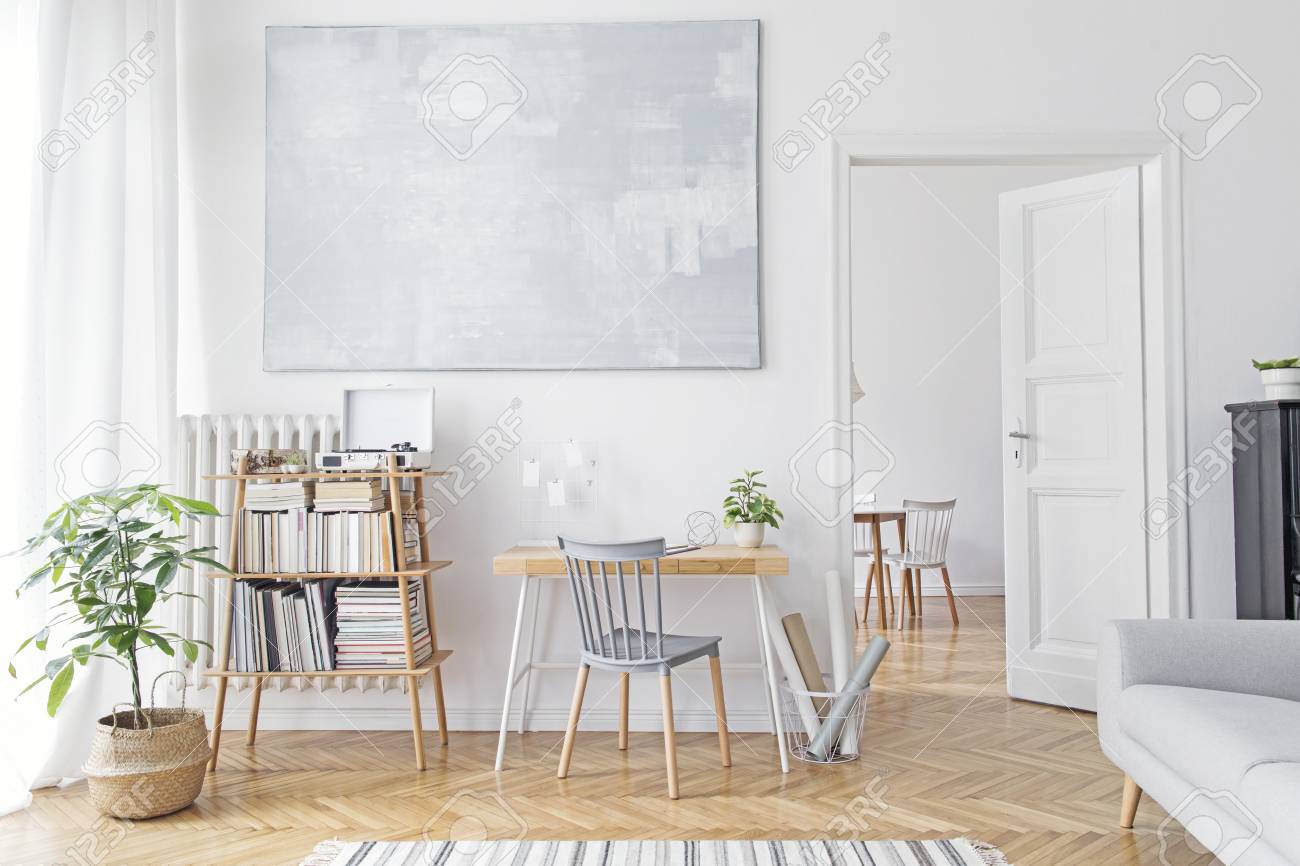 Stylish scandinavian home decor of interior with creative wooden desk, sofa, bamboo bookstand with accessories, books and plants Open space and living room. Brown wooden parquet and stylish carpet. - 120054940 Stylish scandinavian home decor of interior with creative wooden desk, sofa, bamboo bookstand with accessories, books and plants Open space and living room. Brown wooden parquet and stylish carpet. - 120054940