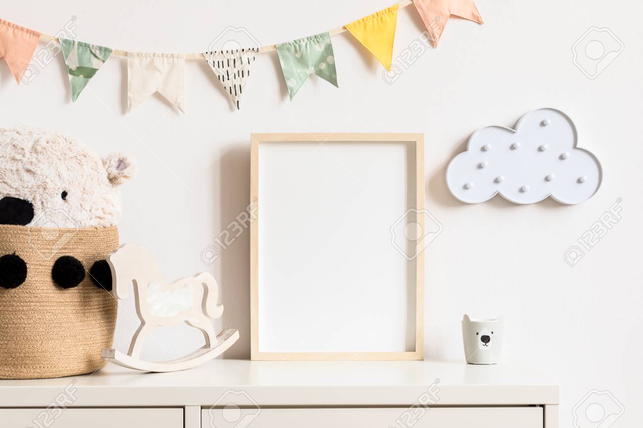 Stylish and modern scandinavian childroom interior with mock up photo or poster frame on the white shelf. Toys, teddy bear in basket, rocking horse and hanging cotton colorful flags and cloud. - 122001431 Stylish and modern scandinavian childroom interior with mock up photo or poster frame on the white shelf. Toys, teddy bear in basket, rocking horse and hanging cotton colorful flags and cloud. - 122001431