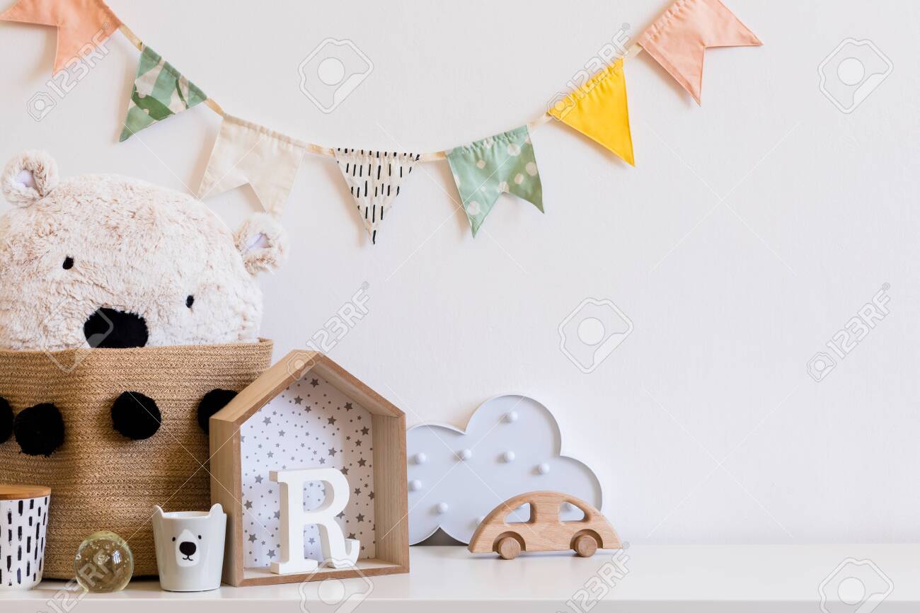 Stylish scandinavian child room with hanging cotton colorful flags on the white wall, boxes, teddy bear in natural basket, toys. wooden accessories and cloud. Real photo. Copy space for inscription. - 122253350 Stylish scandinavian child room with hanging cotton colorful flags on the white wall, boxes, teddy bear in natural basket, toys. wooden accessories and cloud. Real photo. Copy space for inscription. - 122253350