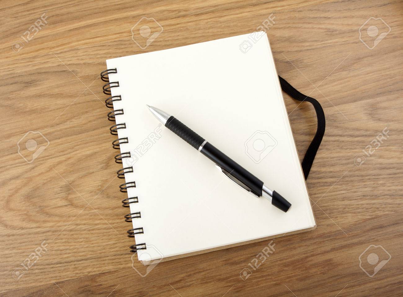 黒のゴムバンドとテーブルの上にペンでリサイクル紙のノート の写真