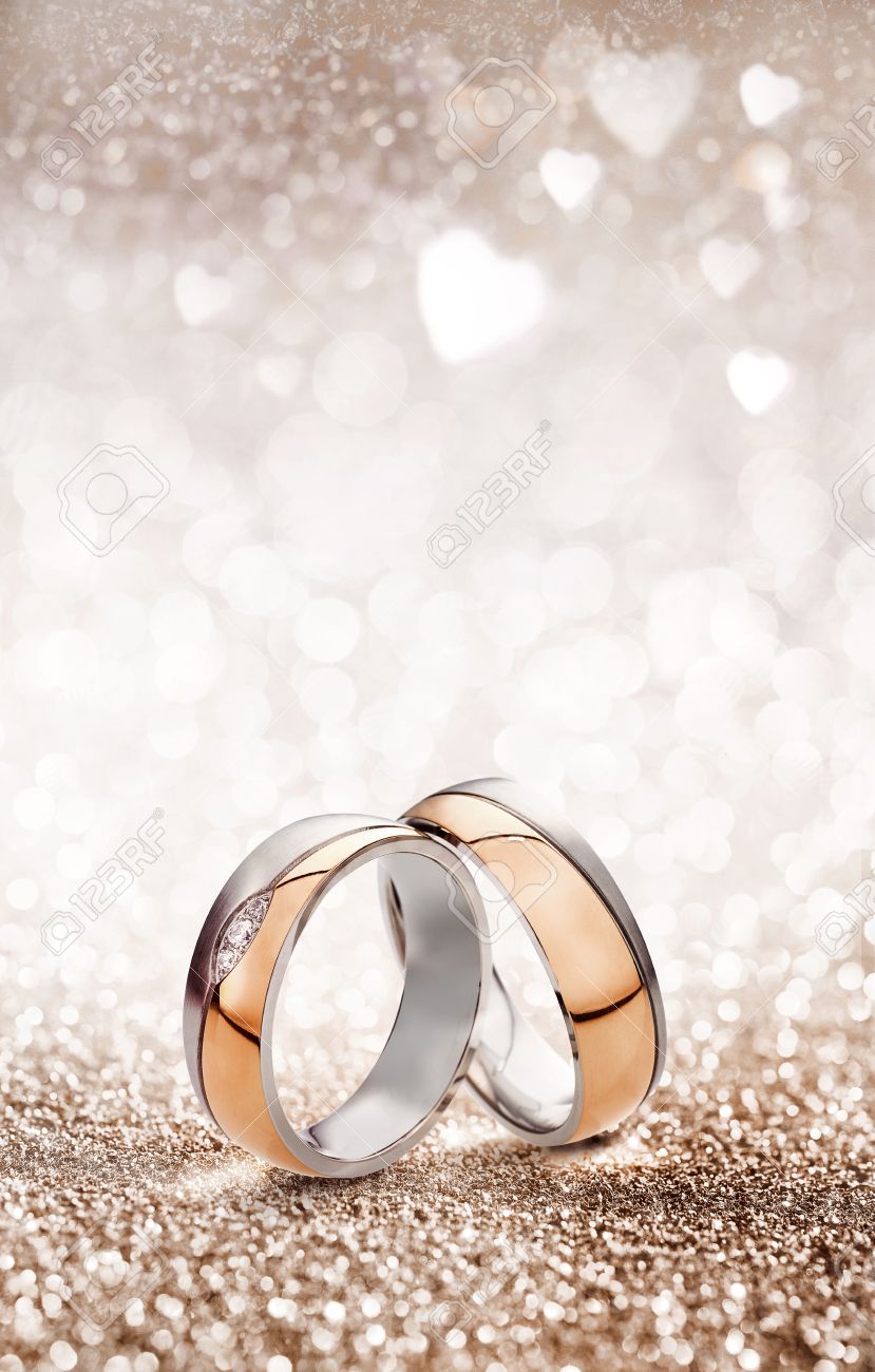 Romantic wedding ring celebration background with two gold rings balancing upright over a light sparkling background with white hearts and copy space for an invitation or greeting card - 62635664 Romantic wedding ring celebration background with two gold rings balancing upright over a light sparkling background with white hearts and copy space for an invitation or greeting card - 62635664