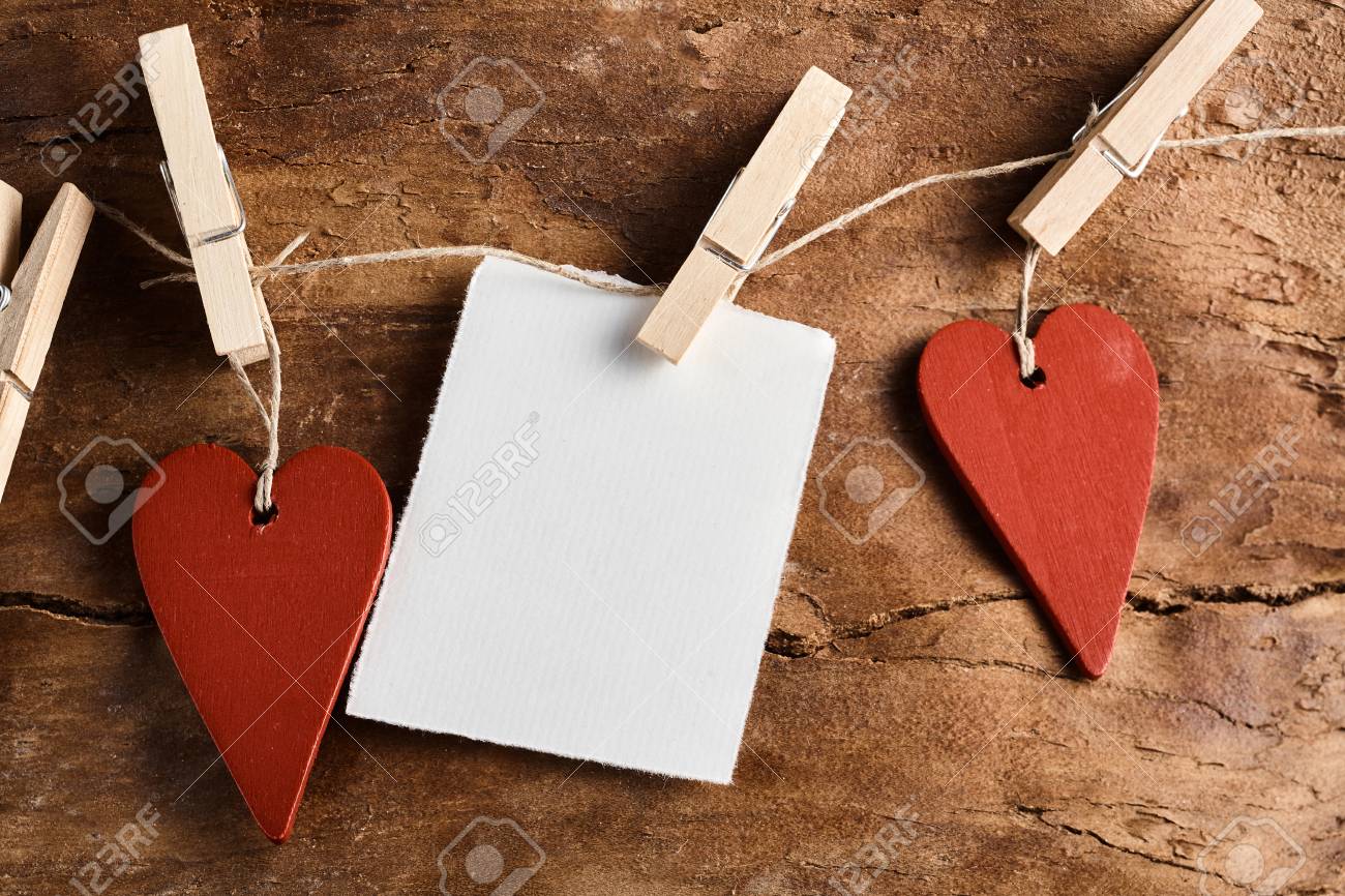 Rustic Valentines Day Background With Two Red Wooden Hearts And A Blank Notelet Hanging From Clothes Rustic Valentines Day Background With Two Red Wooden Hearts And A Blank Notelet Hanging From Clothes