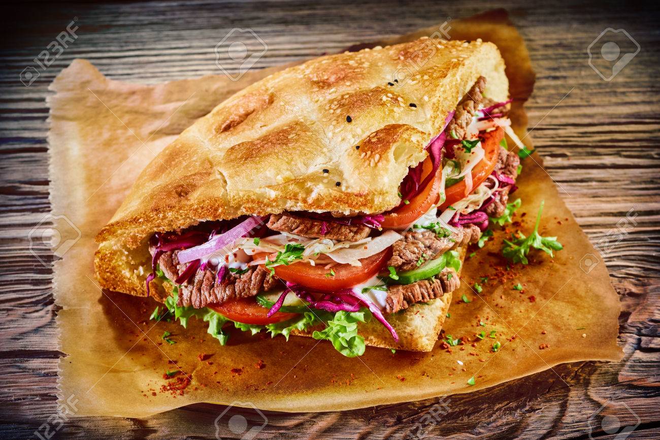 Le Delicieux Kebab De Doner Turc Sur Le Pain De Pita Avec De La Viande Rotie Grillee A Partir D Une Rotissoire Verticale Traditionnelle Servie Avec Des Ingredients Sales Frais Sur Du Papier