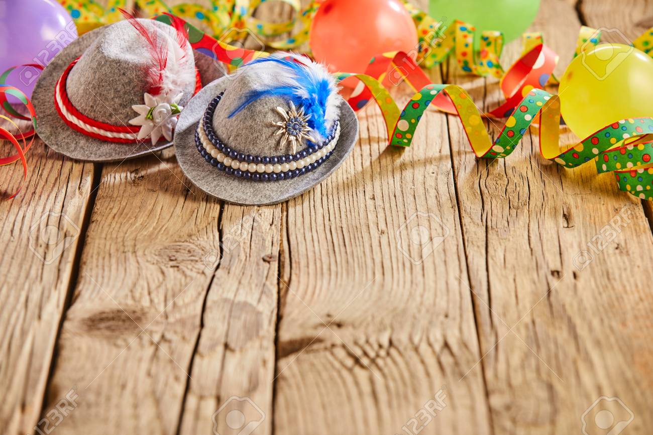 Small hats with feathers stuck in them and round multicolored balloons sitting on rustic wooden table - 110080823 Small hats with feathers stuck in them and round multicolored balloons sitting on rustic wooden table - 110080823