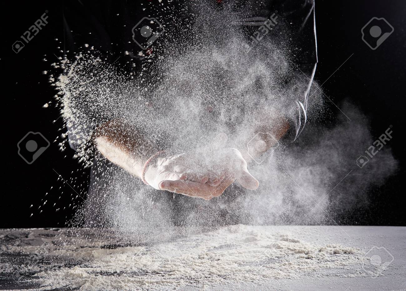 Restaurant worker in black suit and latex gloves wiping white powdery flour off hands onto rectangular - 110811417 Restaurant worker in black suit and latex gloves wiping white powdery flour off hands onto rectangular - 110811417