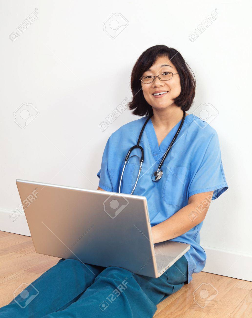 Smiing Woman Nurse Or Doctor Seated On Floor With Laptop Computer