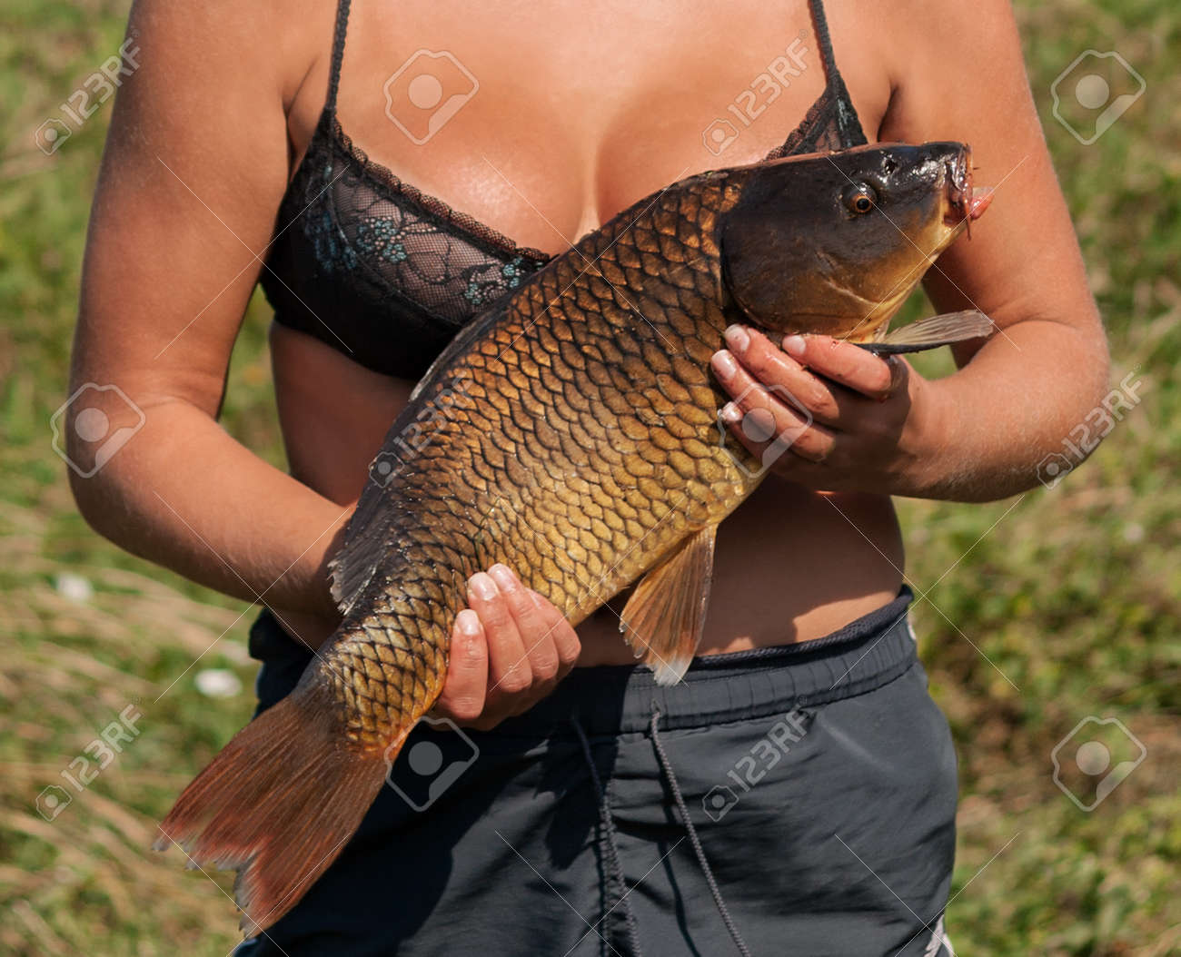 セクシーな幸せな漁師の女の子鯉釣り金魚。日焼けした肌の女性釣り人、巨乳エロゲームの鯉釣り、大きな鯉の魚のトロフィーを手に。の写真素材・画像素材  Image 121112204