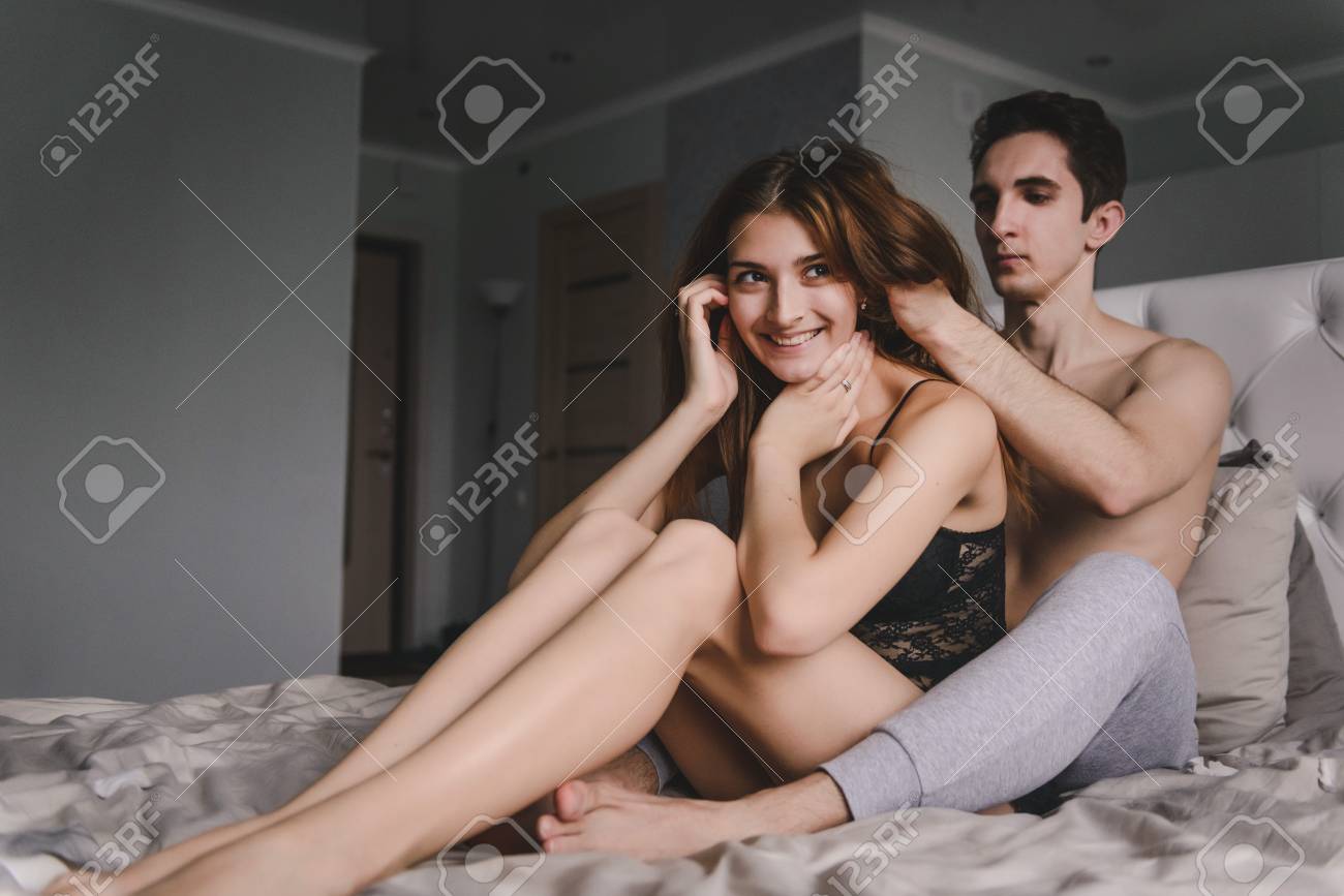 liebespaar im bett frau sitzt zwischen den beinen der manner chemise aus schwarzer spitze mit einer jungen frau der mann zerzauste die haare der