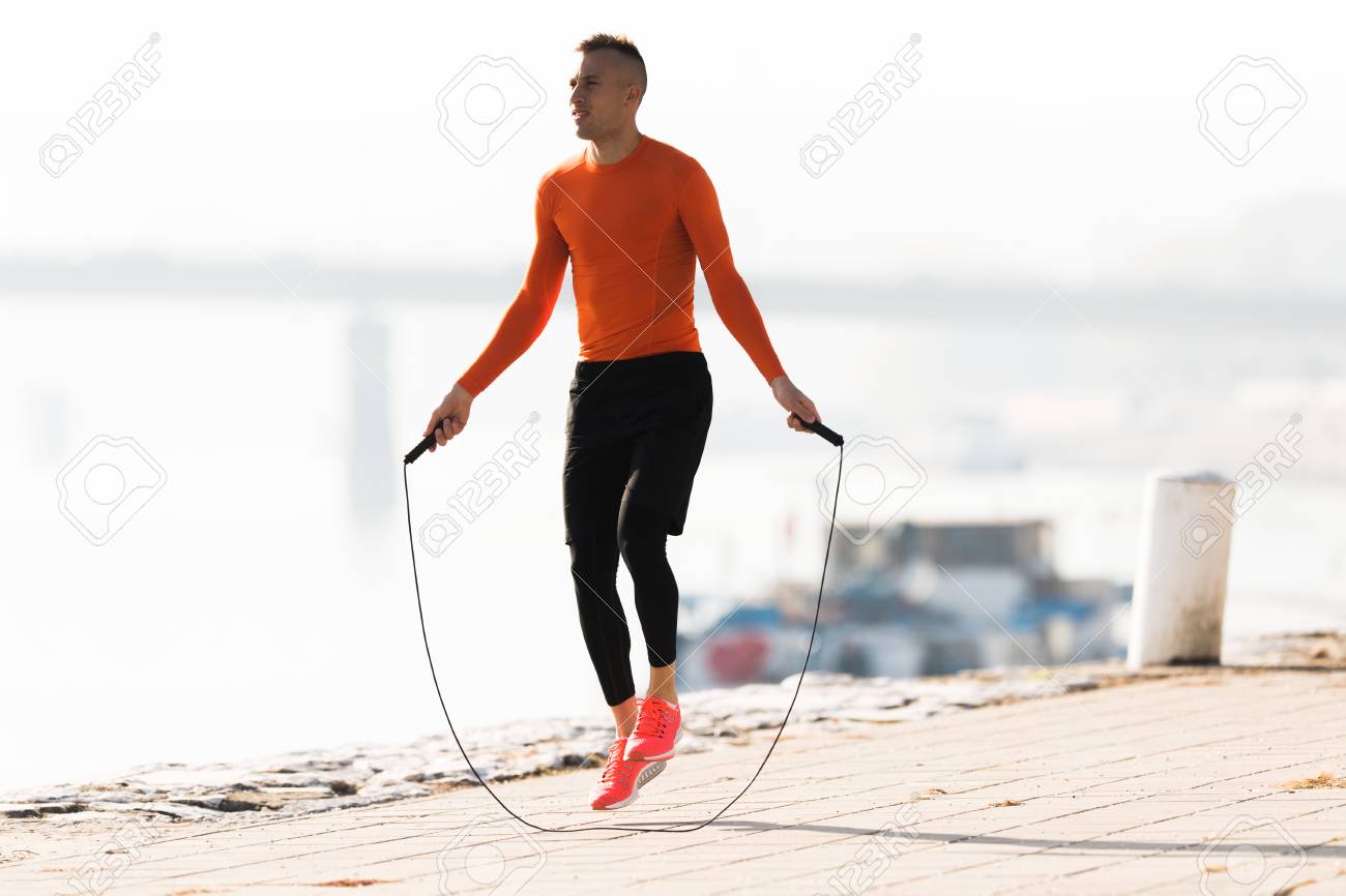 Handsome young man wearing sportswear and skipping rope at quay during autumn - 91171869 Handsome young man wearing sportswear and skipping rope at quay during autumn - 91171869