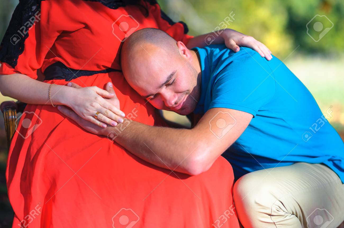 夫が妊娠中の妻 思いやり そして気配りのおなかに耳を適用します の写真素材 画像素材 Image