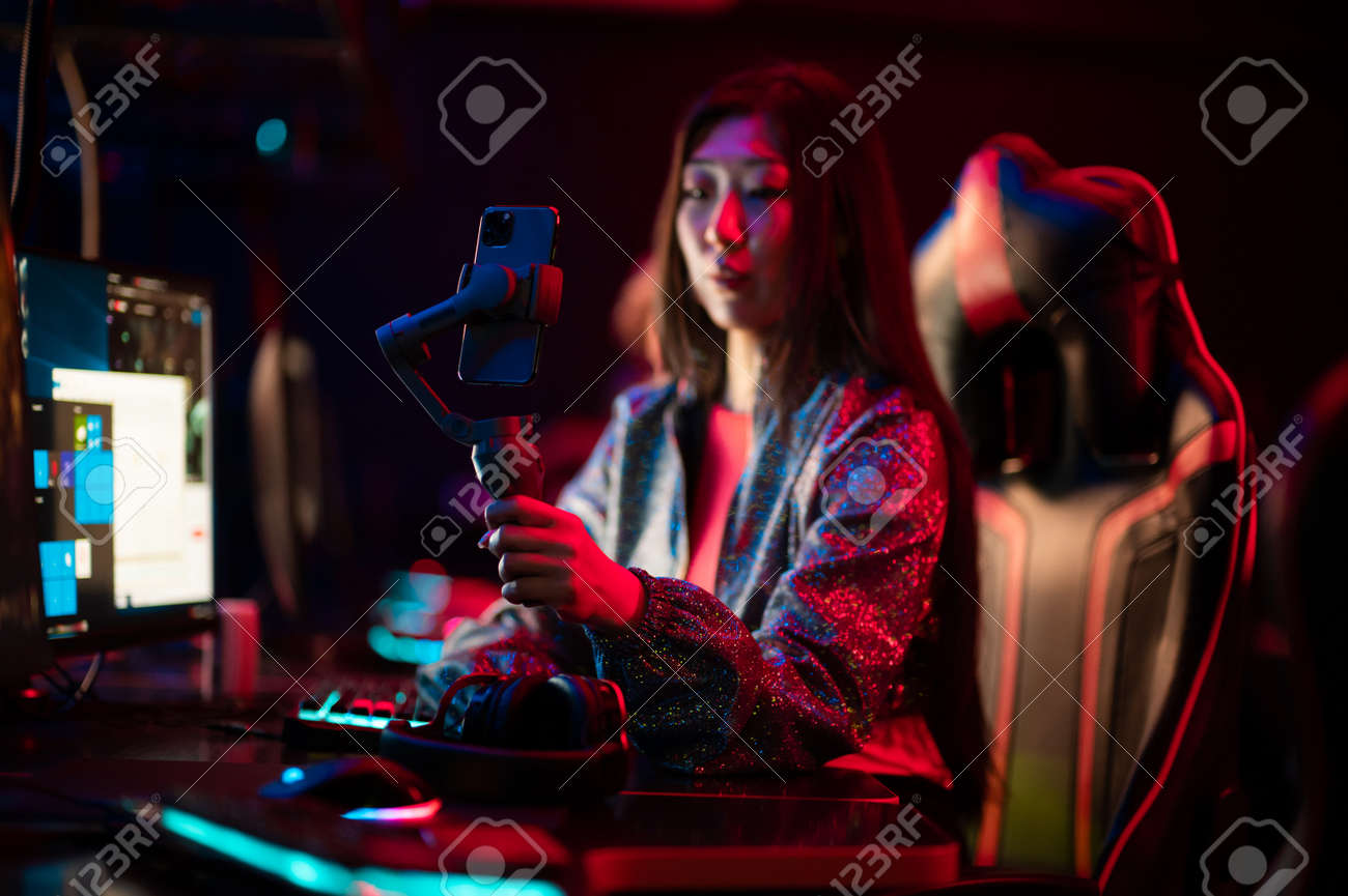 A young chinese gamer participates in esports competitions. Conducts an online broadcast and stream on a social network. Gimbal and smartphone. - 170401108 A young chinese gamer participates in esports competitions. Conducts an online broadcast and stream on a social network. Gimbal and smartphone. - 170401108