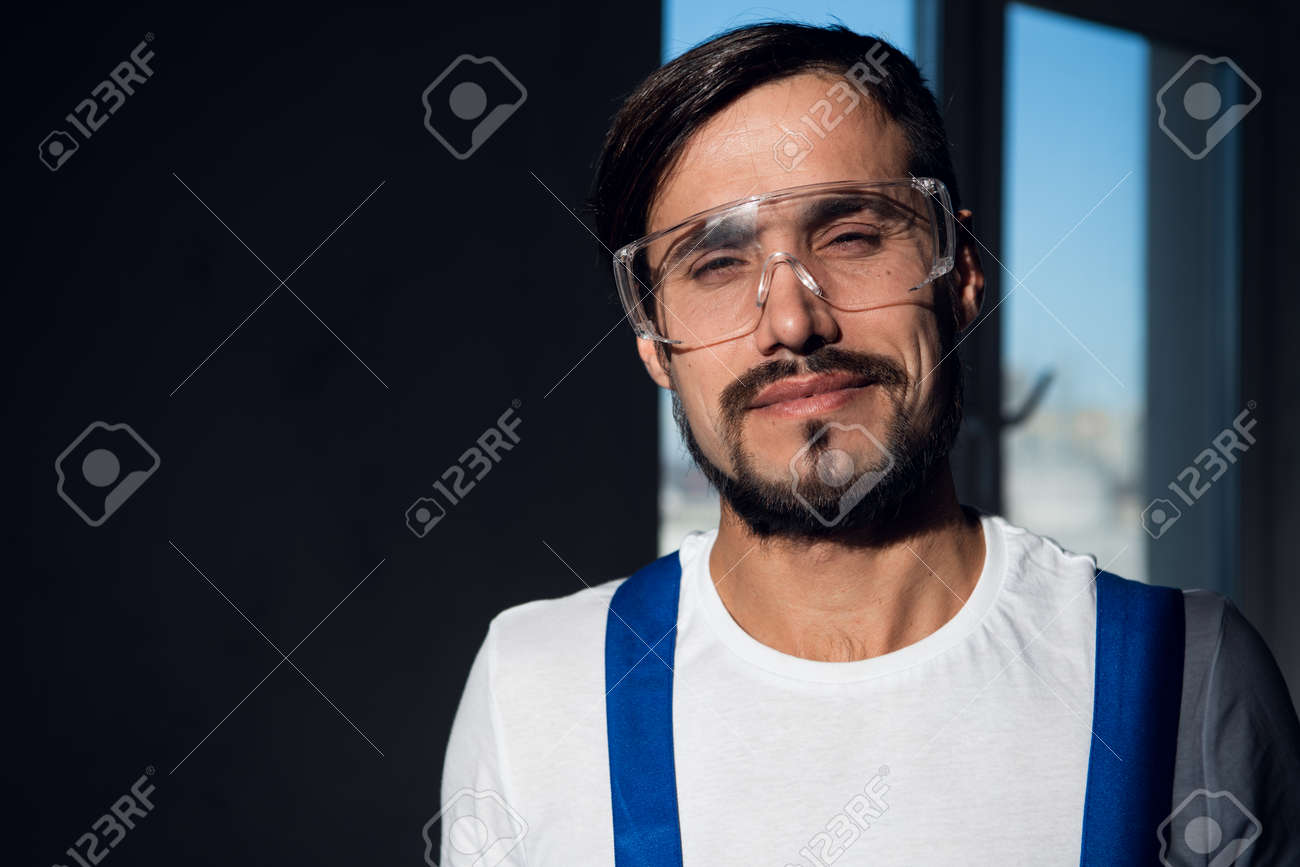 Repairer in blue overalls, white shirt and goggles - 170308238 Repairer in blue overalls, white shirt and goggles - 170308238
