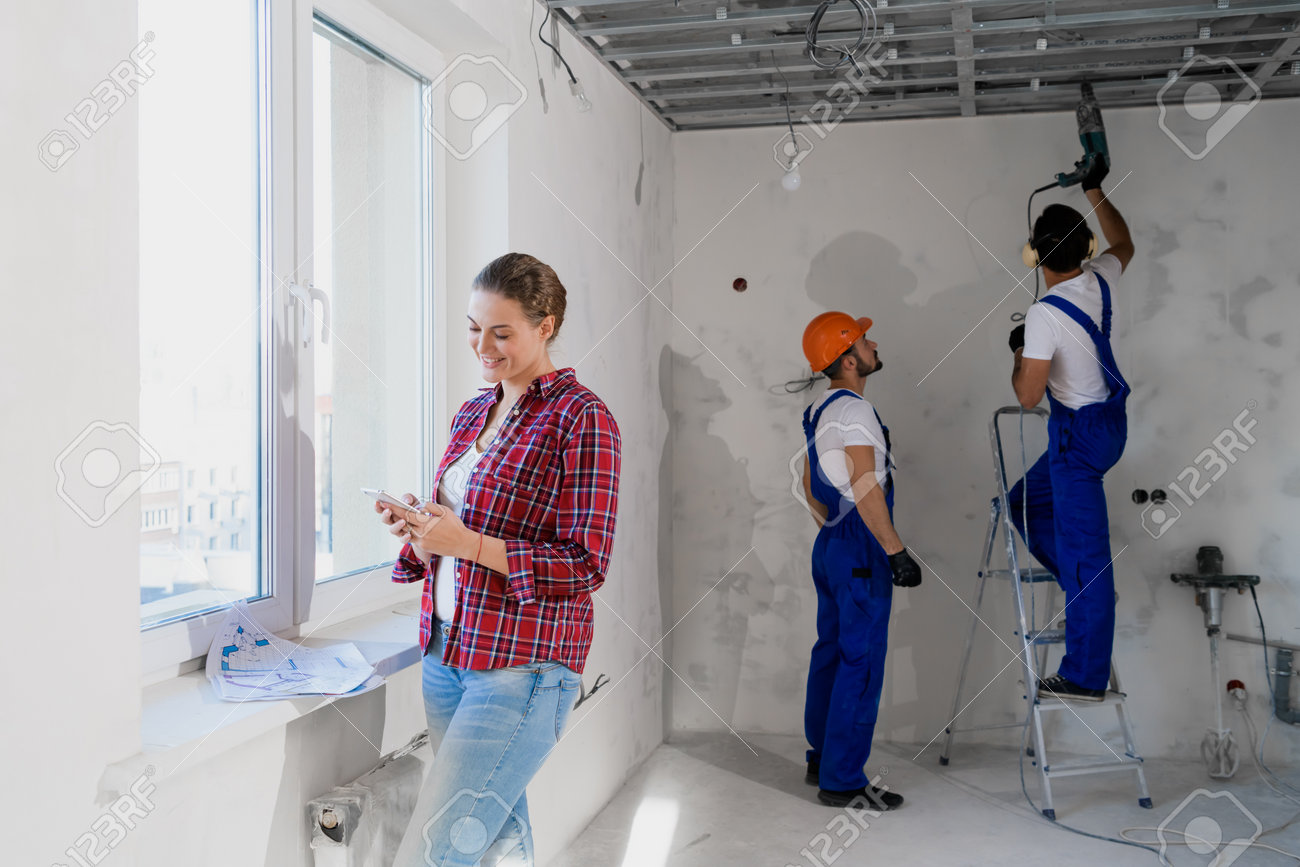 Builders use drill and stepladder, woman typing on the phone - 170308295 Builders use drill and stepladder, woman typing on the phone - 170308295