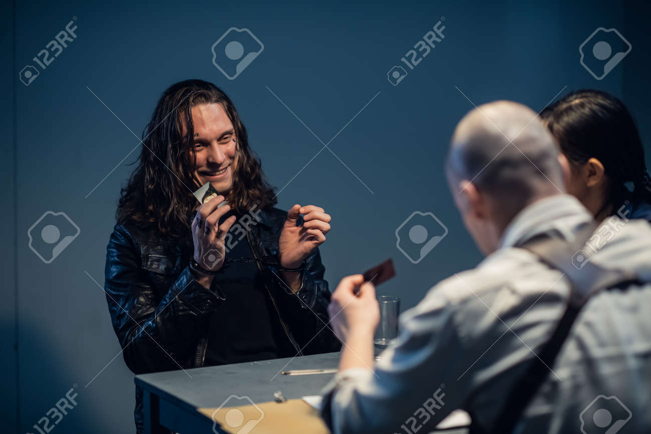 Interrogation of a homicidal maniac in the interrogation room. A police detective sits at a table with a suspect. - 170401000 Interrogation of a homicidal maniac in the interrogation room. A police detective sits at a table with a suspect. - 170401000