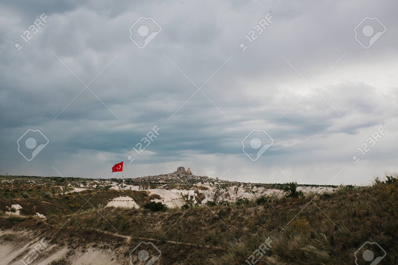 劇的な夜空を背景にトルコのカッパドキアの丘の美しい景色 彼らはこれらの場所の主要な自然の魅力の一つです 丘の上のトルコ国旗 の写真素材 画像素材 Image