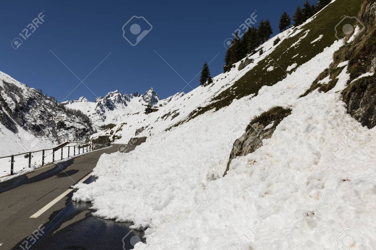 a snow slide blocks a road in the alps of switzerland stock photo