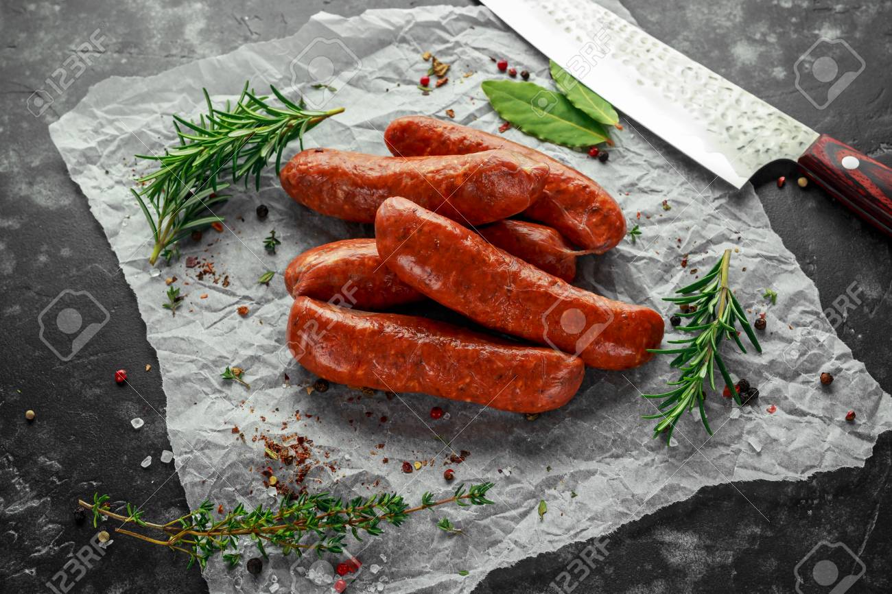 Freshly made raw breed butchers sausages in skins with herbs on crumpled paper. - 97489238 Freshly made raw breed butchers sausages in skins with herbs on crumpled paper. - 97489238