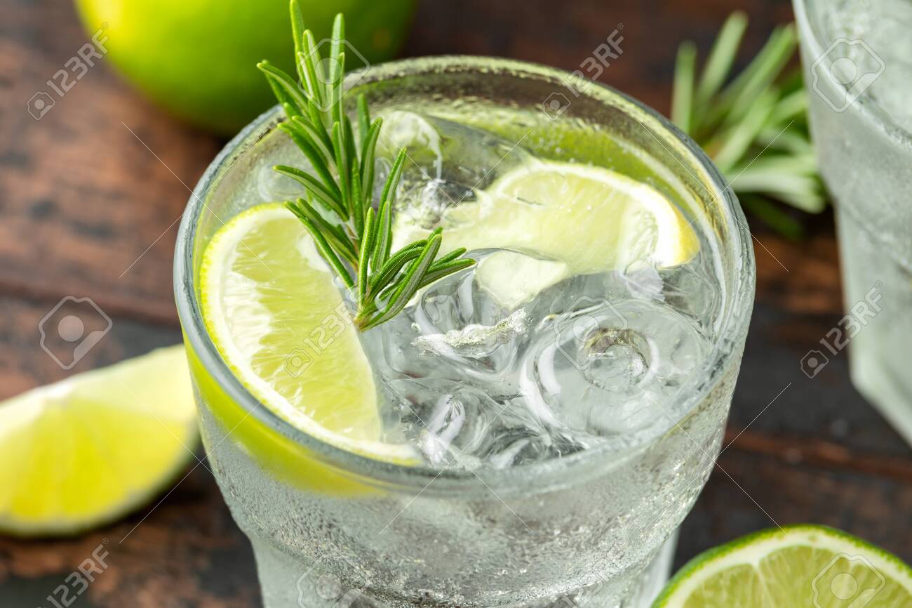 Gin and Tonic Alcohol drink with Lime, Rosemary and ice on wooden table. - 129859271 Gin and Tonic Alcohol drink with Lime, Rosemary and ice on wooden table. - 129859271