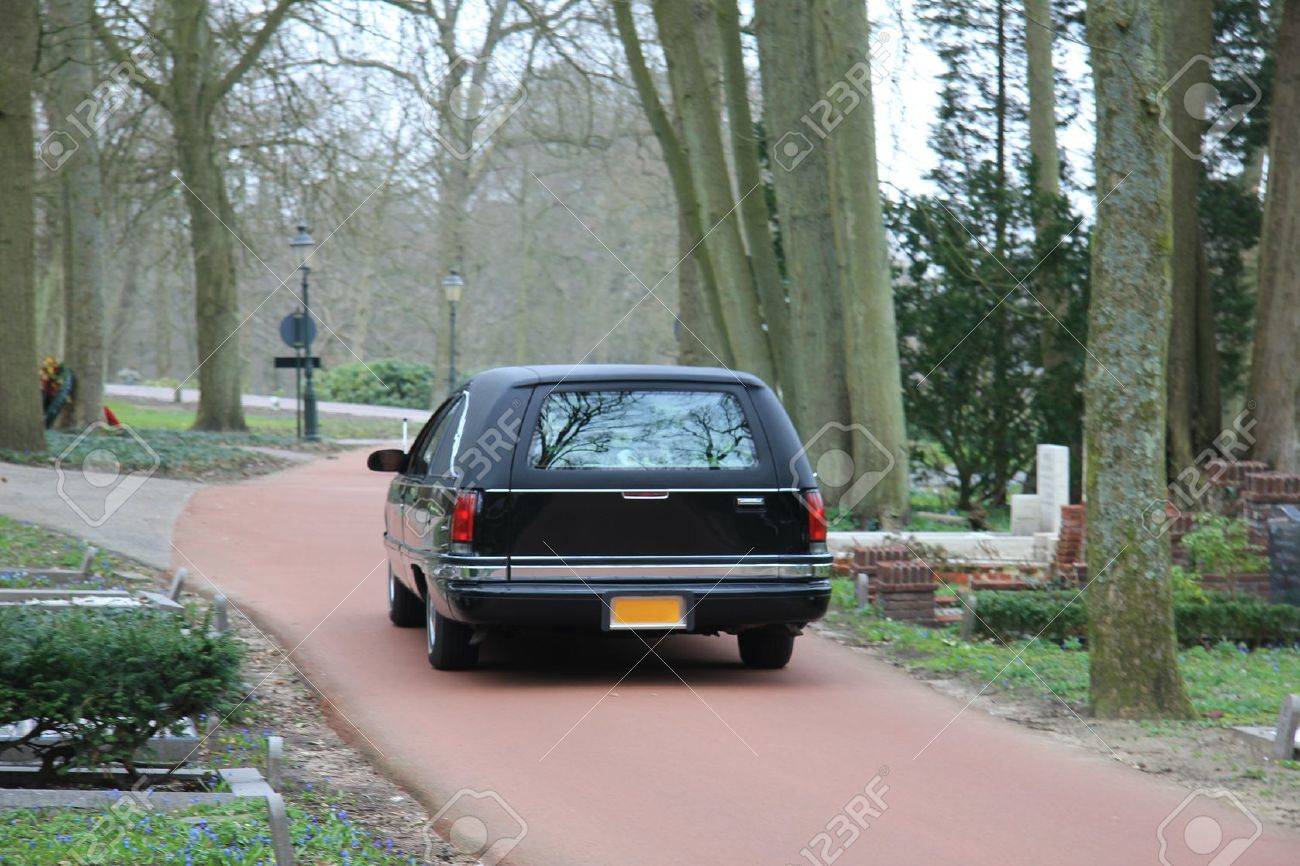 A black hearse on a forest cemetery, driving slow - 13198308 A black hearse on a forest cemetery, driving slow - 13198308