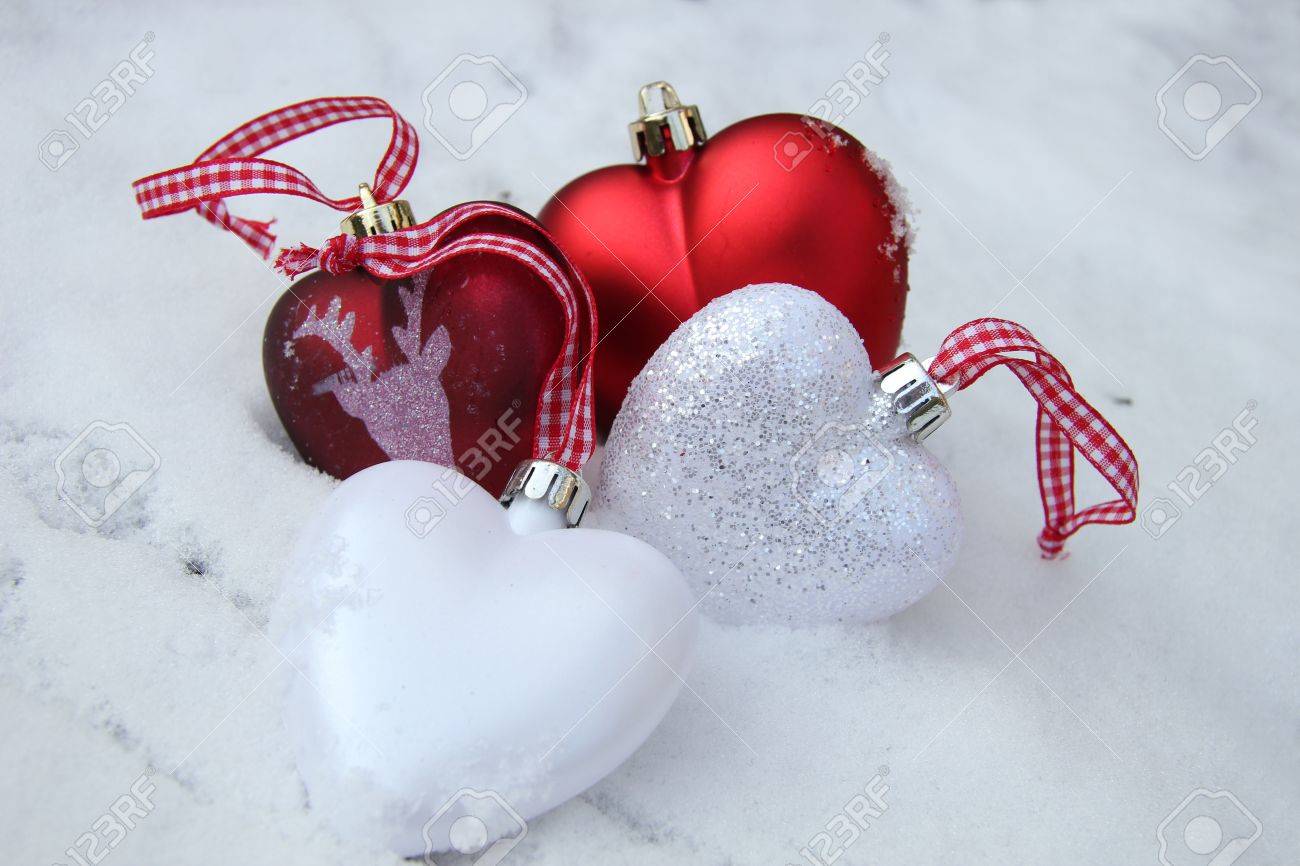 white and red heart shaped ornaments in fresh fallen snow stock