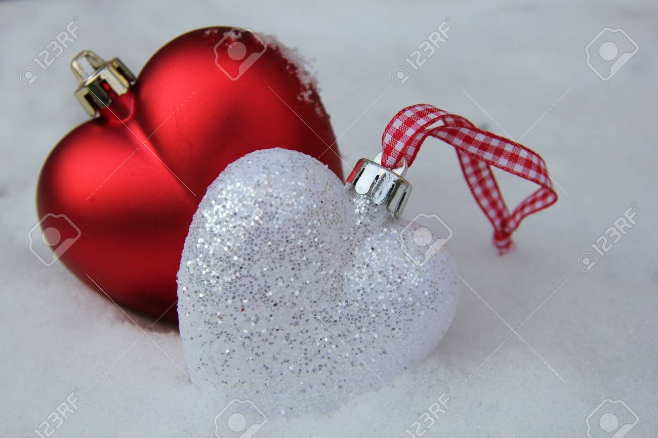 white and red heart shaped ornaments in fresh fallen snow stock