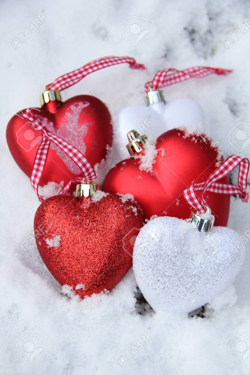 white and red heart shaped ornaments in fresh fallen snow stock