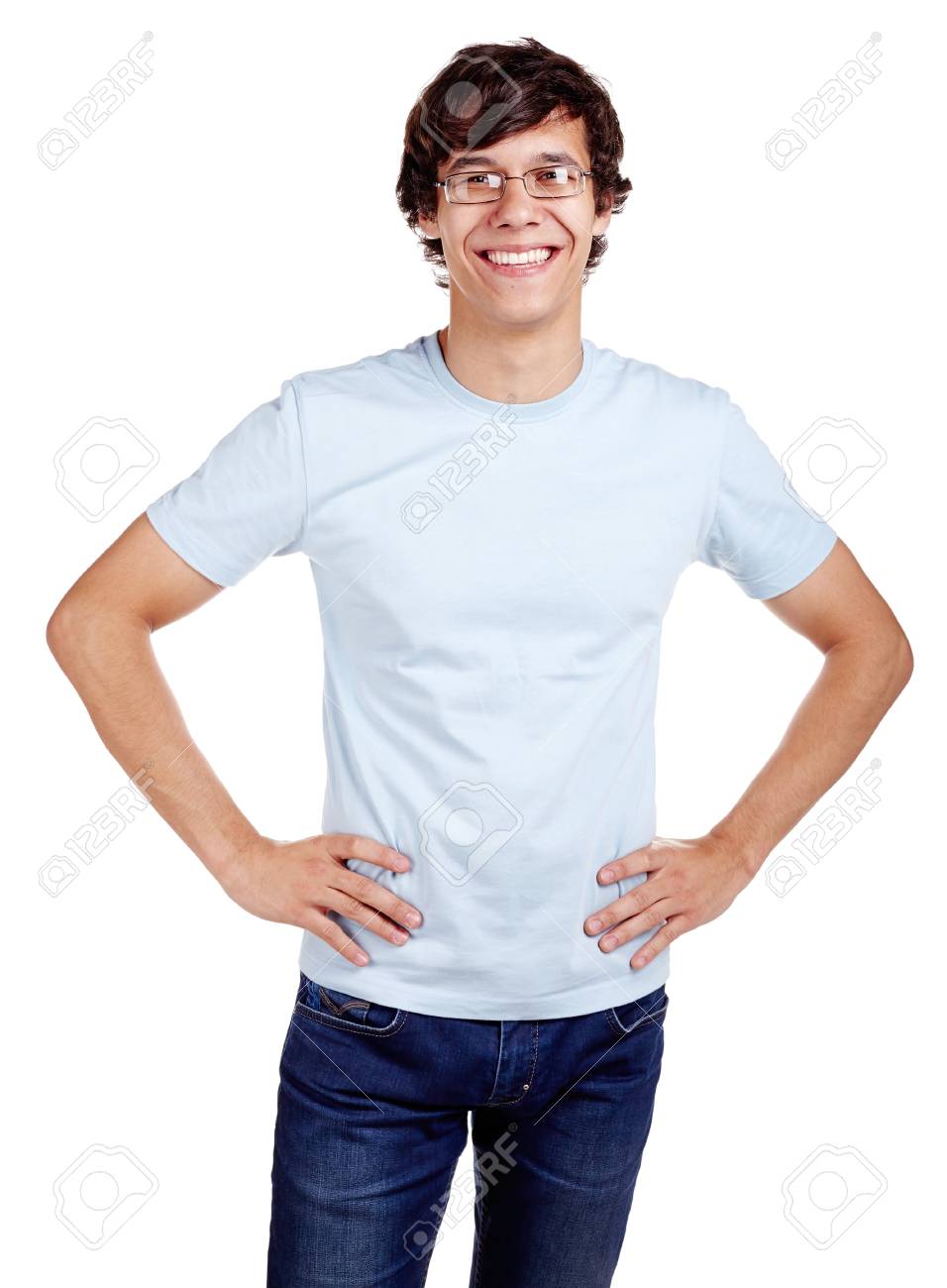 眼鏡 青い T シャツとジーンズの腰に手を立ち 笑みを浮かべて白い背景の上分離された若いヒスパニックの男性の肖像画 の写真素材 画像素材 Image