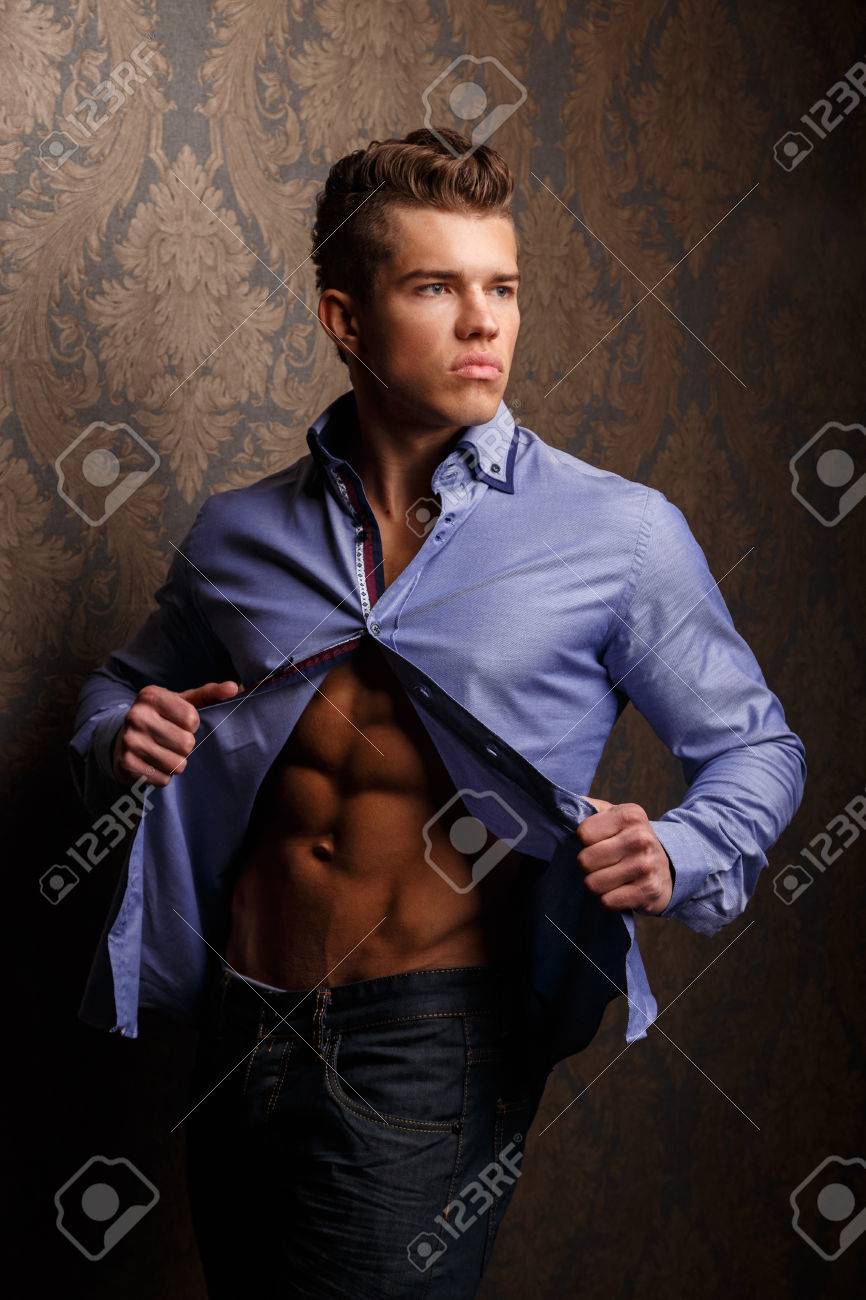 fashion portrait of man in shirt showing his abs and poses over