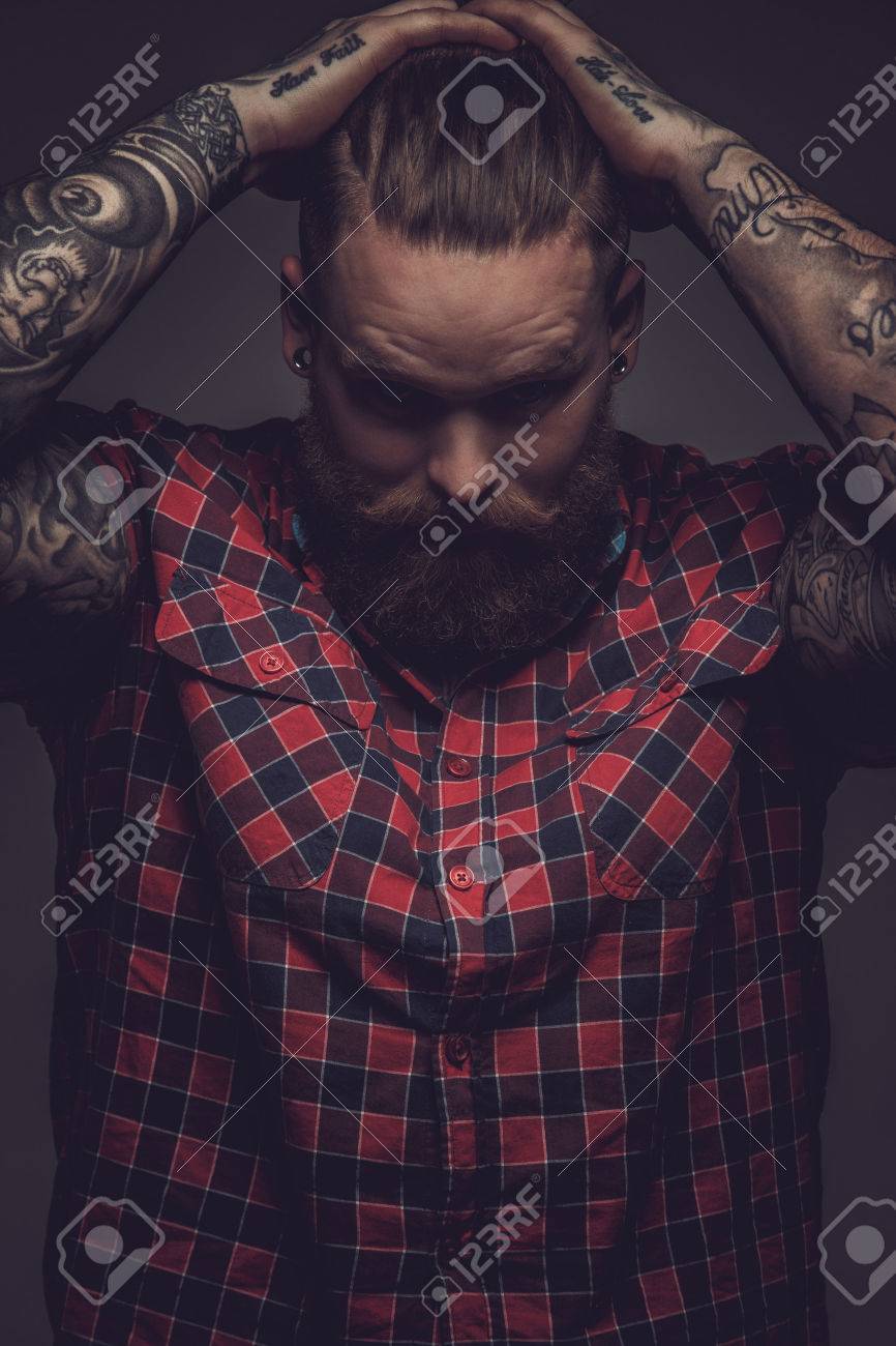 Brutal guy with beard and tattooes holding his head. Isolated on grey background. - 46987637 Brutal guy with beard and tattooes holding his head. Isolated on grey background. - 46987637