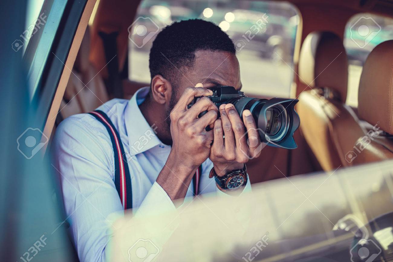 A blackman shooting on dslr from the car. - 55283374 A blackman shooting on dslr from the car. - 55283374