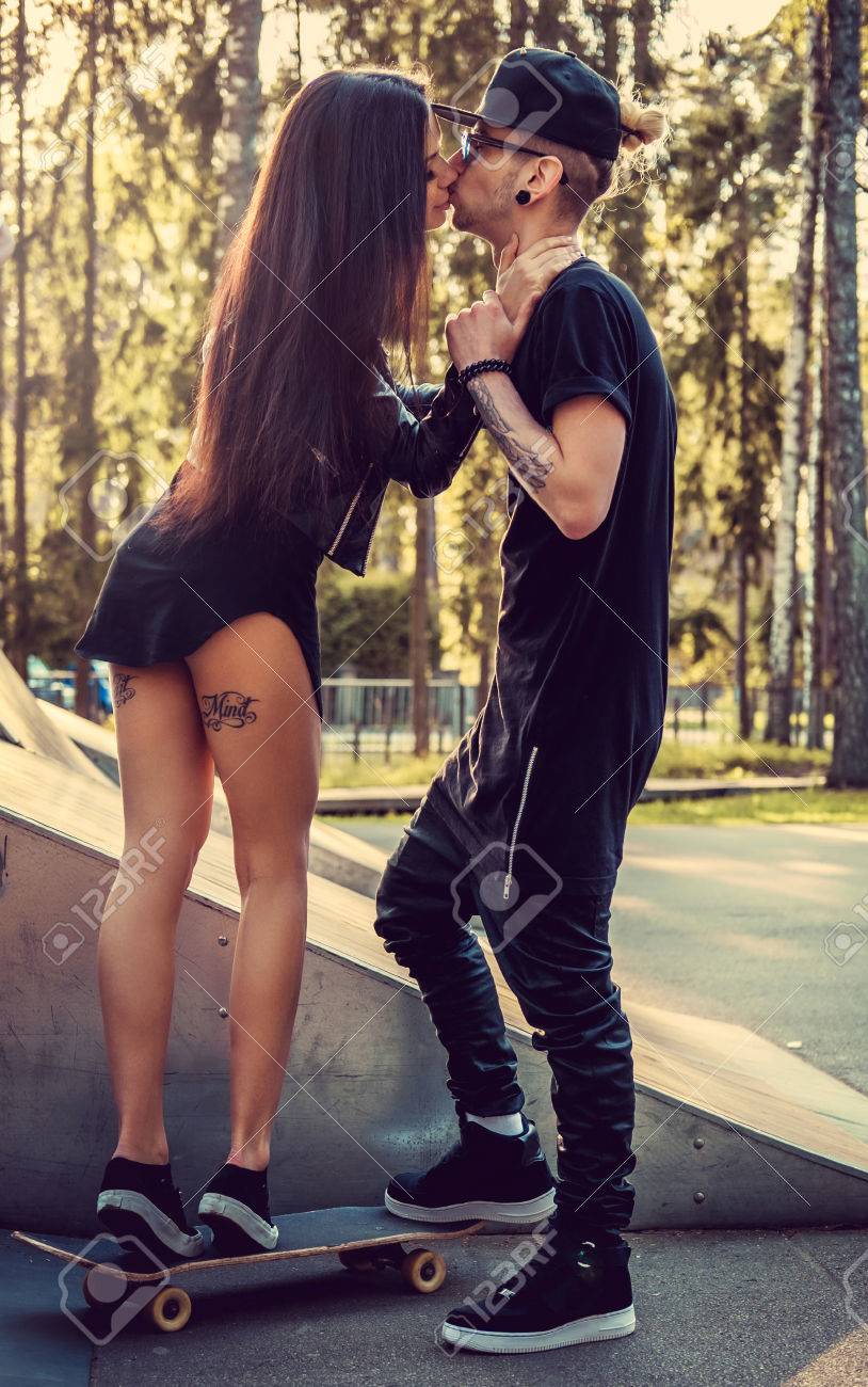 彼の腕の入れ墨をした男のキスのスケート ボードのセクシーな女性 の写真素材 画像素材 Image