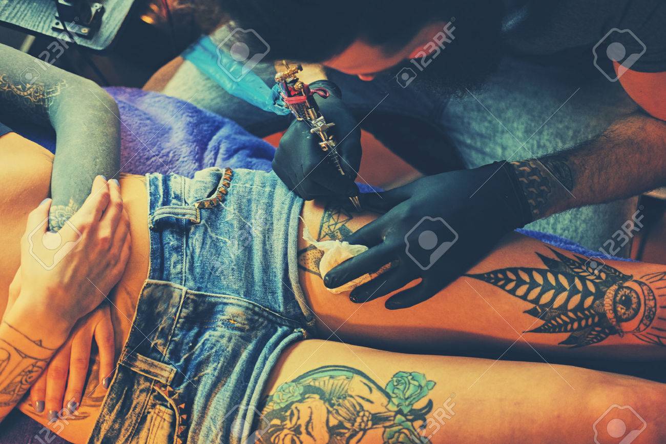 Close up image of the bearded tattoo male artist makes a tattoo on a female leg. - 76338037 Close up image of the bearded tattoo male artist makes a tattoo on a female leg. - 76338037