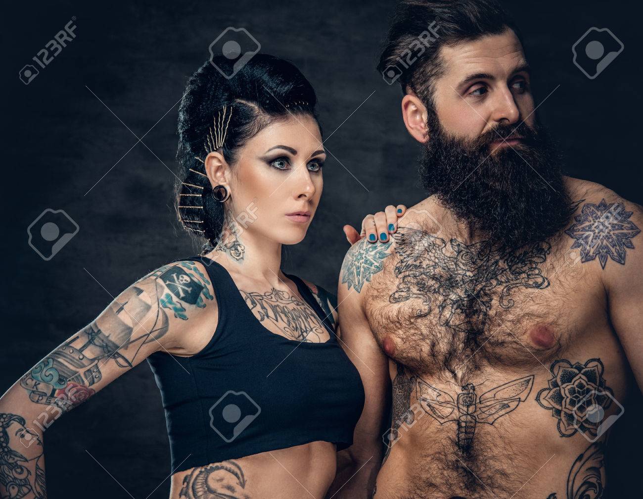 Portrait De Torse Nu Tatoué Mâle Hipster Barbu Et Femme Brune Avec De Lencre De Tatouage Sur Son Torse Sur Fond Gris Foncé