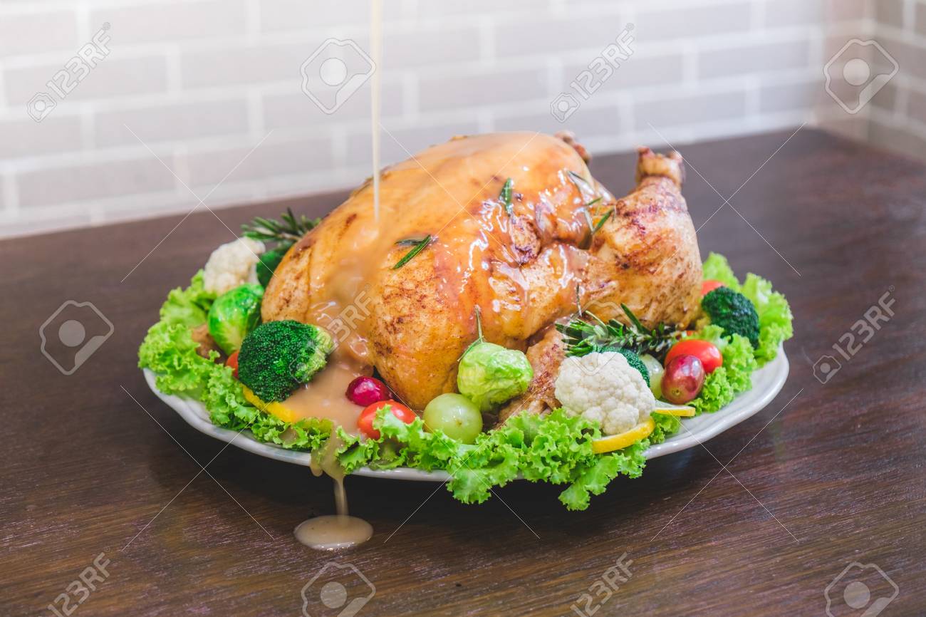 Roasted turkey stuffing garnished with Vegetables served with gravy sauce on a rustic style table. Christmas Dinner - 68623479 Roasted turkey stuffing garnished with Vegetables served with gravy sauce on a rustic style table. Christmas Dinner - 68623479