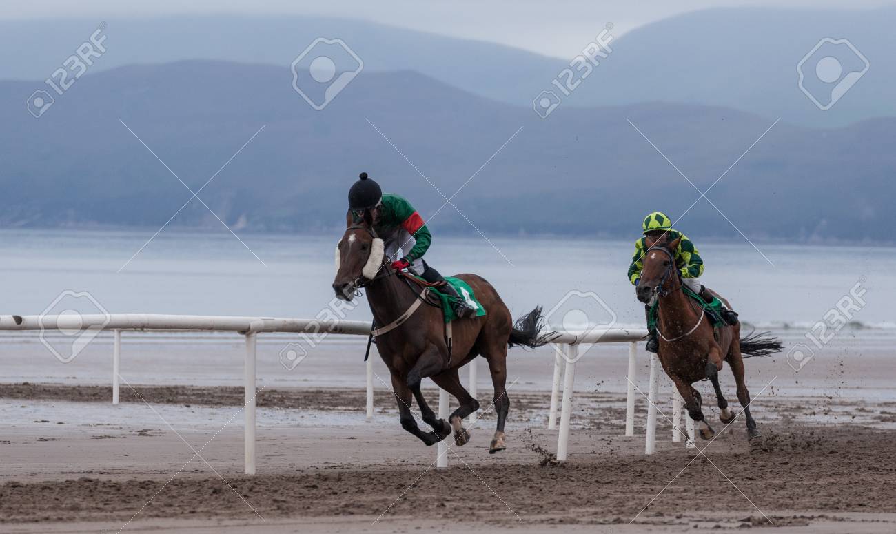 Galloping Race Horse And Jockey On The Beach Stock Photo