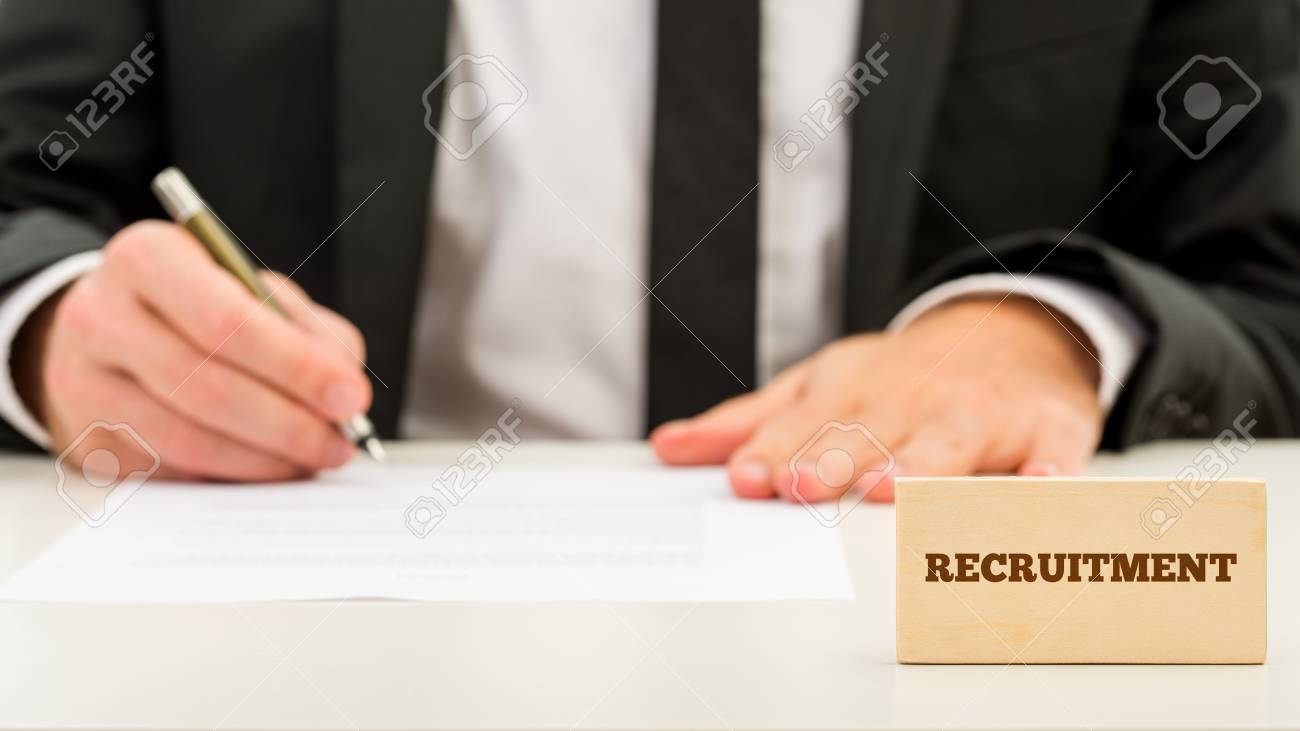 applicant completing a job application with a small wooden block completing a job application