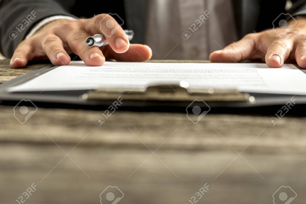 Closeup of male hand about to sign a subscription or application papers clipped on blue folder on wooden desk. - 44284781 Closeup of male hand about to sign a subscription or application papers clipped on blue folder on wooden desk. - 44284781