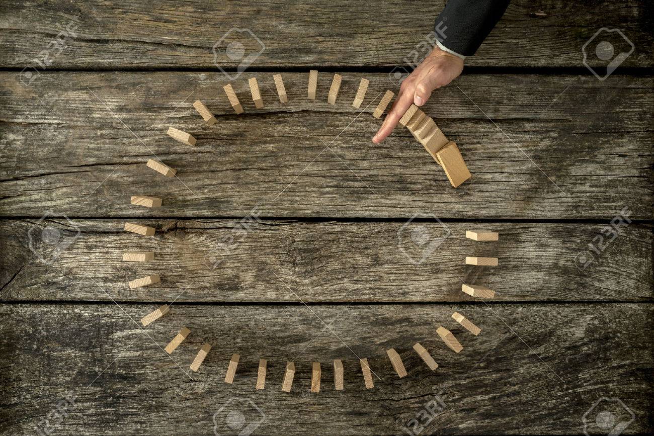 Businessman stopping falling dominos placed in a circle with his hand. Conceptual of crisis and problem management. - 50168057 Businessman stopping falling dominos placed in a circle with his hand. Conceptual of crisis and problem management. - 50168057