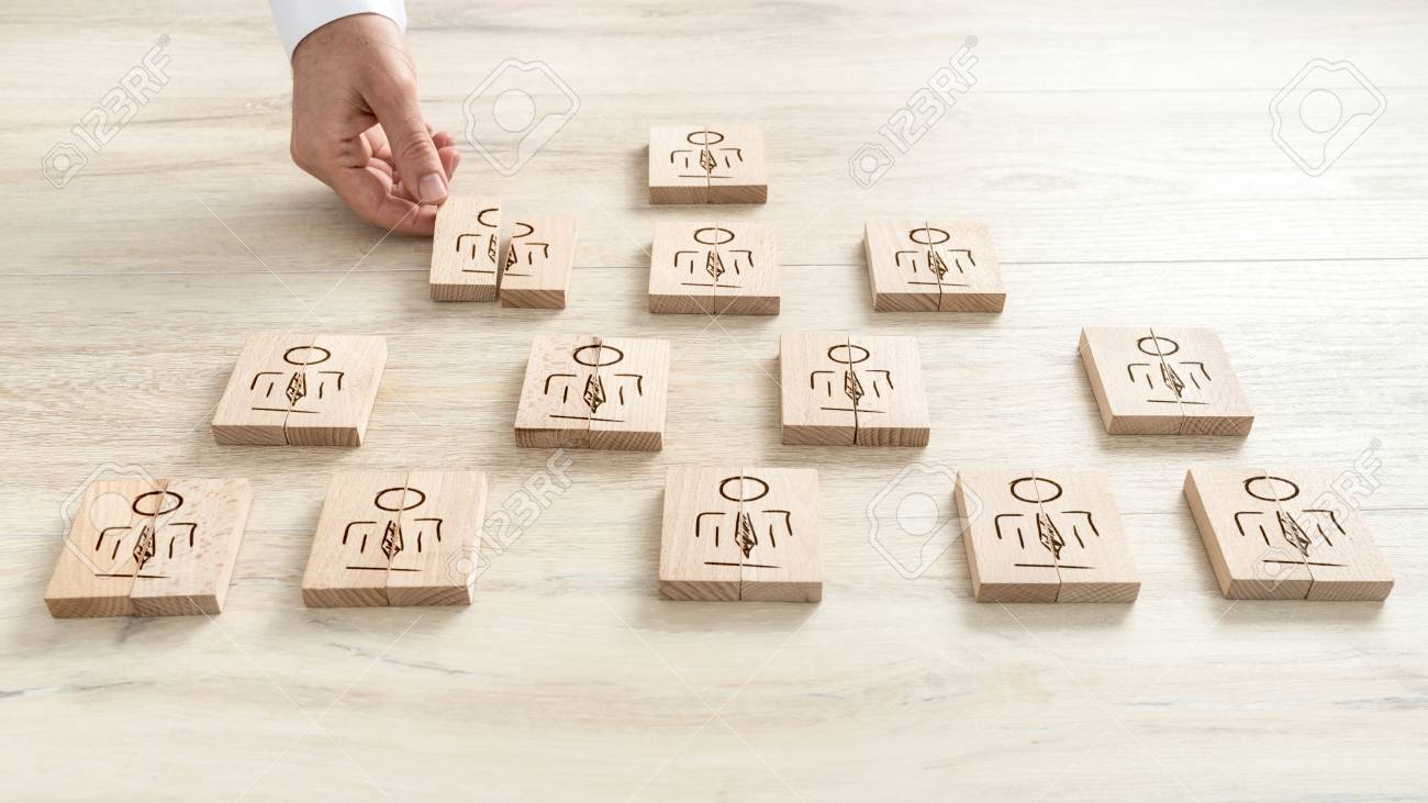 Human resources concept with a businessman arranging a series of wooden blocks depicting people into a pyramid. - 91995270 Human resources concept with a businessman arranging a series of wooden blocks depicting people into a pyramid. - 91995270
