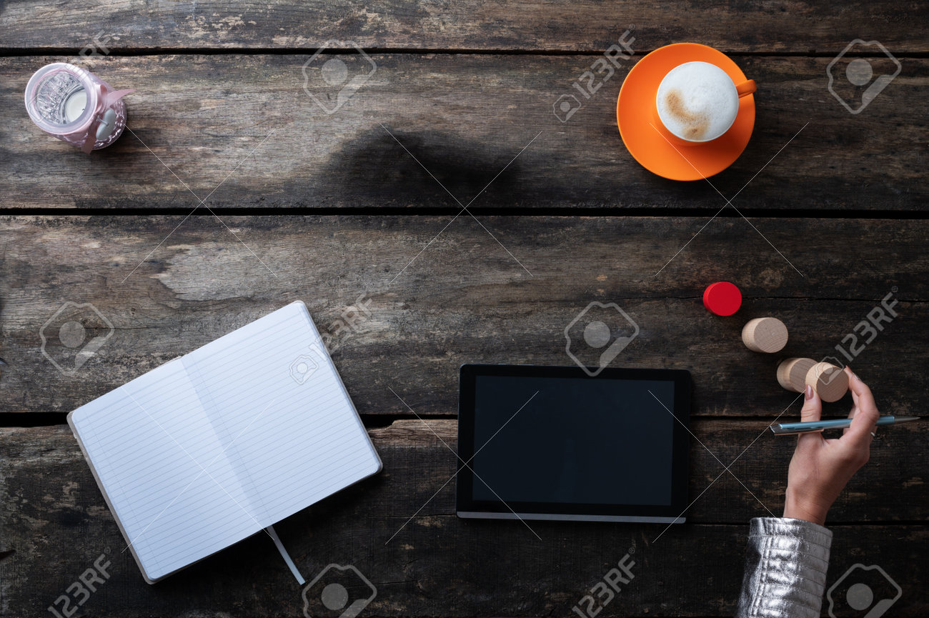 Top view of a woman working and brainstorming using digital tablet, notepad and stacking wooden blocks. - 171099187 Top view of a woman working and brainstorming using digital tablet, notepad and stacking wooden blocks. - 171099187