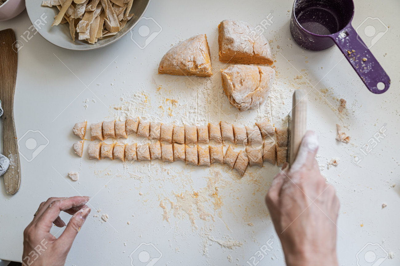 Top view of a woman making homemade vegan sweet potato gnocchi on flour dusted kitchen counter. - 170456468 Top view of a woman making homemade vegan sweet potato gnocchi on flour dusted kitchen counter. - 170456468