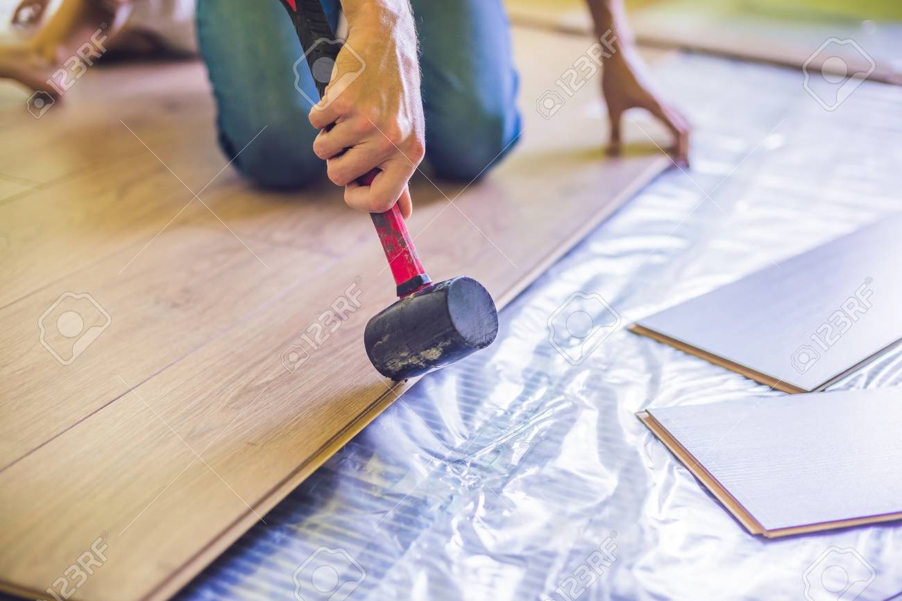 Man Installing New Wooden Laminate Flooring On A Warm Film Floor