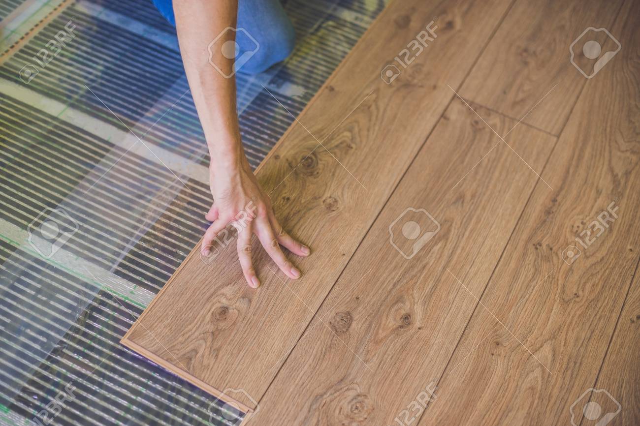 Man Installing New Wooden Laminate Flooring On A Warm Film Floor