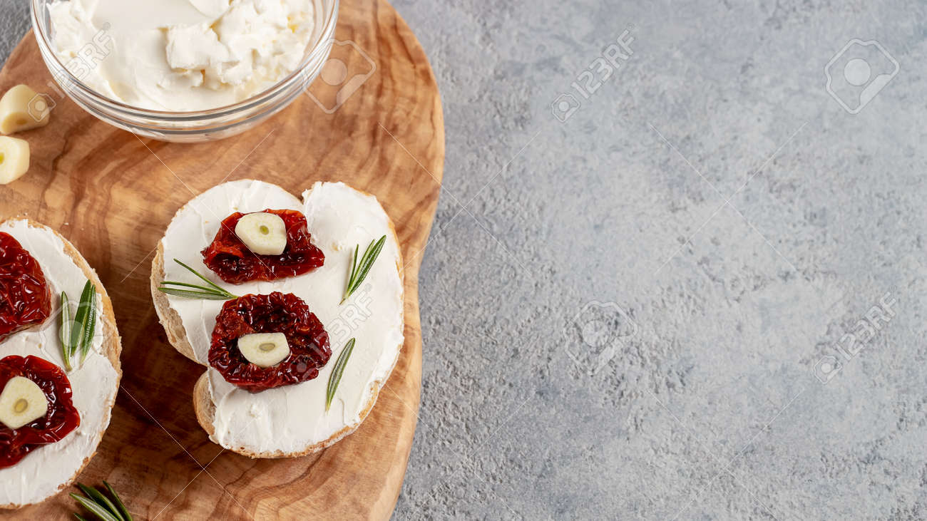 Homemade sandwiches with cream cheese and sun-dried tomatoes on a wooden board of olive - delicious healthy breakfast, copy space, flat lay - 170506410 Homemade sandwiches with cream cheese and sun-dried tomatoes on a wooden board of olive - delicious healthy breakfast, copy space, flat lay - 170506410