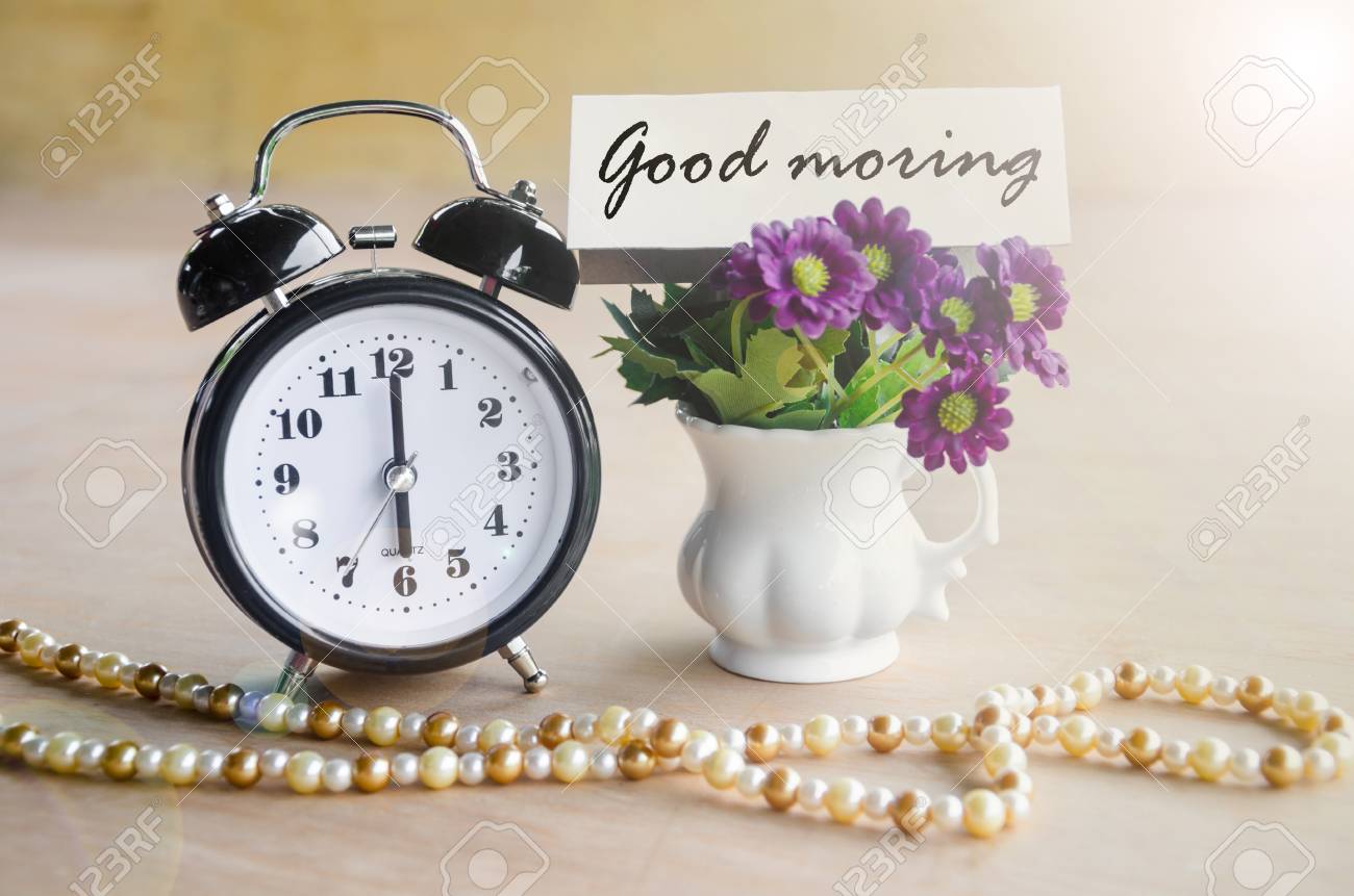 alarm clock and good morning tag with violet flower on wooden