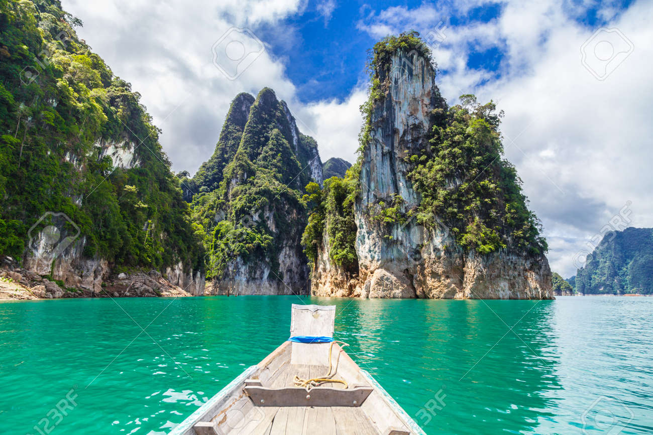 Wooden Thai traditional long-tail boat on a lake with mountains at Ratchaprapha Dam or Khao Sok National Park, Surat Thani Province, Thailand - 156539301 Wooden Thai traditional long-tail boat on a lake with mountains at Ratchaprapha Dam or Khao Sok National Park, Surat Thani Province, Thailand - 156539301