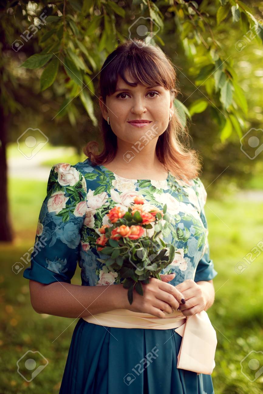 Young beautiful woman in floral dress posing in Park with a bouquet of flowers, on green background summer nature. - 66915686 Young beautiful woman in floral dress posing in Park with a bouquet of flowers, on green background summer nature. - 66915686