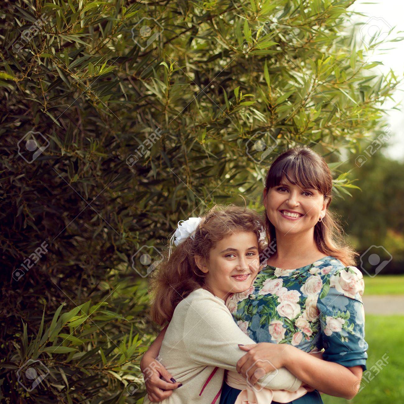 Beautiful young mother in a floral dress and daughter teen 10 years hugging in the Park in the summer, good family relationships - 66915733 Beautiful young mother in a floral dress and daughter teen 10 years hugging in the Park in the summer, good family relationships - 66915733