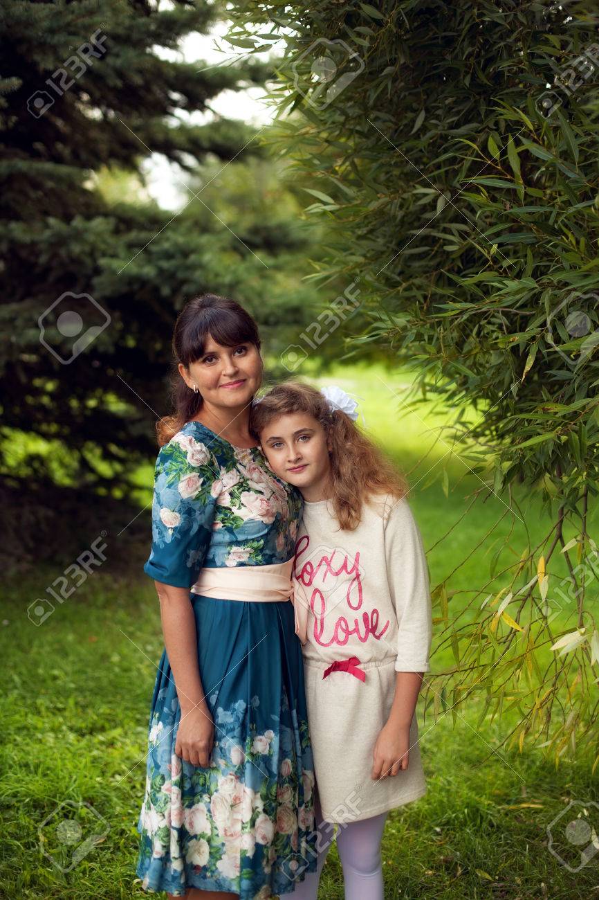 Happy family on a walk in the Park in the open air, mother and daughter 10 years hugging on green summer background - 66916483 Happy family on a walk in the Park in the open air, mother and daughter 10 years hugging on green summer background - 66916483