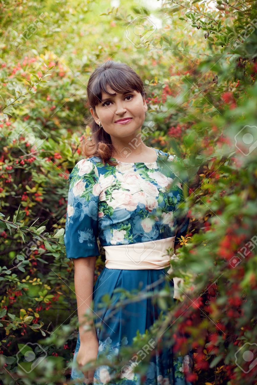 beautiful happy brunette woman in the park on a warm summer day, a girl in a floral dress walks outdoors - 66916810 beautiful happy brunette woman in the park on a warm summer day, a girl in a floral dress walks outdoors - 66916810